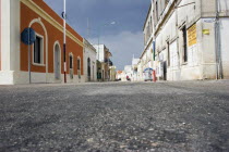 Characteristic empty street lined with old coloured buildings.  Low angle shot from tarmac level.summerholidayvacationmiddaysiesta timeasphaltMagna GreciaColored European Italia Italian Southe...