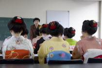 Gion area  the neighbourhood where Geisha live  study and perform.  Maiko apprentice Geisha attending a class at Mia Garatso school of Geisha  seated with backs to camera looking towards female teache...