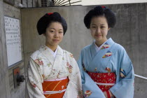 Two Maiko apprentice Geisha wearing patterned kimono  standing outside their house in the Gion District  the neighbourhood where Geisha live  study and perform.Far EastGeikotradtioncultureJapanes...