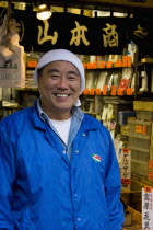 Tsukiji fish market.  Three-quarter portrait of smiling Japanese man selling herbs at the worlds biggest fish and food market the known as  the stomach of Tokyo.smilehappy facemoodemotionexpressi...