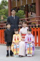 Fushimi-Inari Taisha  Fushimi-Ku Fukakusa Yabunouchi-cho.  Japanese family wearing formal suits and traditional kimonos posing for photographs at the entrance of the Fushimi-Inari Taisha shrine dedica...