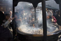 Asakusa Kannon or Senso-ji Temple.  Japanese people wafting smoke from incense burner or joukoro over themselves in belief that it will keep them in good health.Shintotraditioncultureshrinereligi...