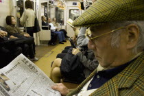 Tokyo Metro.  Elderly Japanese man wearing tweed cap and jacket reading a newspaper while travelling on the Tokyo Metro.transportationvehicleundergroundpassengersrailwaytrainFar EastAsia Asian...