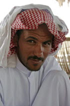Portrait of a Bedouin man with short  trimmed beard and moustache  wearing traditional Arabic dress of keffiyeh and jalabiya.nomadnomadiccultureethnicityracial charateristicsracejelabiyajallab...