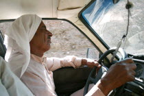 Bedouin taxi driver wearing traditional Arabic dress of keffiyeh and jalabiya  singing while driving.cultureethnicityraceracial characteristicsjallabiyajelabiyavehicletransportationAfrican Cl...