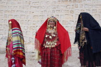 Three Tunisian women wearing traditional dress  golden jewelry and ornaments  relatives of a Tunisian bride whose wedding they are celebrating on the borders of the Sahara Desert.marriageceremonymo...