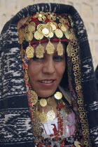 Head and shoulders portrait of Tunisian bride wearing traditional dress  gold jewelry and decorated head dress in preparation for her wedding held on the edge of the Sahara Desert.marriage  ceremony...