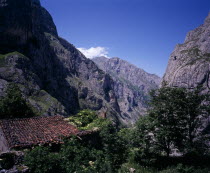 View north down Arroyo del Tejo Valley from Bulnes El Castillo with steep sided  eroded limestone cliffs and red tiled roof of ruined barn in foreground.