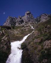 Artificial waterfall  overflow from Canal de Poncebos which supplies the hydro-electric plant at Poncebos with jagged limestone cliffs of Cueto del Pando above.