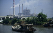 Boat travelling down the Grand Canal between Suzhou and Wuxi. Power station with smoke emitting from cooling towers and large industrial buildings under construction.Asia Asian Chinese Chungkuo Jhong...