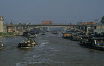 Barges travelling down the Grand Canal between Suzhou and Wuxi. Engineering vehicles driving across bridge over canal.Asia Asian Chinese Chungkuo Jhonggu� Zhonggu� Traveling