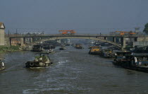 Barges travelling down the Grand Canal between Suzhou and Wuxi. Engineering vehicles driving across bridge over canal.Asia Asian Chinese Chungkuo Jhonggu Zhonggu Traveling