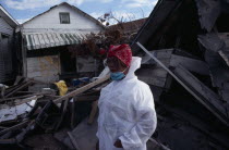 Aftermath of 2005 Hurricane Katrina  woman wearing protective clothing standing amongst wood and other debris from destroyed buildings.windstorm American disaster Female Women Girl Lady North Ameri...