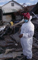 Aftermath of 2005 Hurricane Katrina  woman wearing protective clothing standing amongst wood and other debris from destroyed buildings.windstorm American disaster Female Women Girl Lady North Ameri...