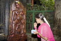 Young woman standing beside shrine depicting Goddess of Fertility  Meenakshi TempleSouthernIndiaIndianAsiaAsianHorizontalInsideIndoorInteriorCultureCulturalHistoricReligionReligiousPray...