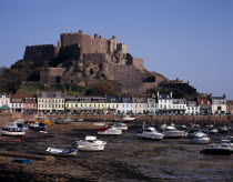 Grouville. Gorey Castle or Mont Orgueil set on hill overlooking village buildings and boats in harbour with the tide out. On the east coast.European Scenic Castillo Castello Northern Europe