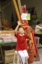 Boy incense seller throws his book up in glee outside the Arhat Temple in downtown ChongqinAsia Asian Chinese Chungkuo Jhonggu Zhonggu Kids One individual Solo Lone Solitary Religious