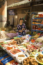 Street market with a smiling woman vendor selling spices  garlic  ginger and other foodstuffs below Ciqiikou Ancient TownAsia Asian Chinese Chungkuo Jhonggu Zhonggu Female Women Girl Lady Happy One...