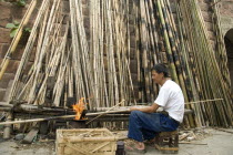 Man strengthening bamboo joints with fireAsia Asian Chinese Chungkuo Jhonggu Zhonggu Male Men Guy One individual Solo Lone Solitary