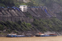 Industrial complex in the Wu Gorge. Line of trucks bring coal from the mines and dump into bunkers from where it flows through pipes to coal barges waiting below on the Yangtze RiverAsia Asian Chines...