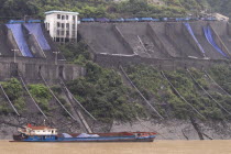 Industrial complex in the Wu Gorge. Line of trucks bring coal from the mines and dump into bunkers from where it flows through pipes to coal barges waiting below on the Yangtze RiverAsia Asian Chines...