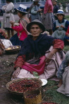 Woman selling cherries from a basket at the Railhead. Near CuscoCuzco American Female Women Girl Lady Hispanic Latin America Latino Peruvian South America