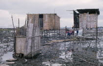 Slum housing with stilt buildings built over untreated sewage. A child seen sitting at doorway and clothes hanging on a washing line above waterAmerican Children Clean Cleaning Equador Hispanic Kids...