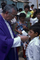 Roman Catholic Bishop giving Communion in Barrio Indio Guayas slum neighbourhood.American Christian Equador Hispanic Kids Latin America Latino Neighbourhood District Religious shanty South America