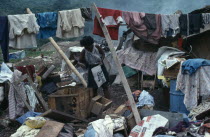 Rubbish sorters house with a woman surrounded by clothes and other recycled items found in the city rubbish tip in barrio Guayas slum neighbourhood American Equador Female Women Girl Lady Hispanic La...