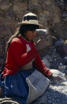 Woman knelling on a Banco Minero de Bolivia sack breaking rocks into small pieces with a hammer at a mine. Near Sucre American Bolivian Chuquisaca Female Women Girl Lady Hispanic Latin America Latino...