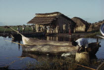 Yau tribe fishermen with Yav boats on Lake Chilwa. Men and children gathered next to thatched huts near waters edge. African Eastern Africa Kids Malawian Male Man Guy