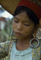 Young Kayan woman harvesting dry hill rice wearing heavy earrings elongating her ear lobes and a large circular hat to protect from the sun. Subgroup of the Dayak indigenous tribes native to BorneoAs...