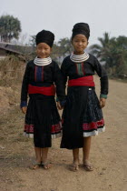 Full length standing portrait of two Meo girls holding hands and smiling wearing traditional dress and neck rings Meo indigenous people2 Asian Classic Classical Happy Historical Indegent Kids Lao...