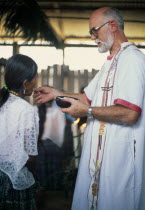 Padre Tiziano an Italian Roman Catholic missionary giving communion to a Q eqchi Indian woman American Central America Christian Female Women Girl Lady Hispanic Latin America Latino Religious