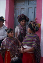 Ixil Indian women and girls gathered together at doorway in conversation. Wearing traditional dress with colourful shawls over shoulders and elaborate head-dress wrapped into the hairAmerican Central...