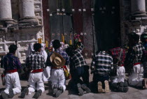 Quiche Indian men kneeling in prayer outside the 16th century church during San Andres Festival on December 8thPrayingAmerican Central America Hispanic Latin America Latino Male Man Guy Religious