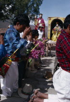 Quiche Indian men knelling in prayer to the saints outside church during San Andres Festival on December 8thAmerican Central America Hispanic Latin America Latino Male Man Guy Religious