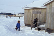 The Great Whale settlement. Cree indigenous community. Women wearing coats with fur hoods walking through deep snow up steps into family house. Great Whale River Crees American Canadian Female Woman...