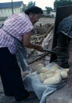 Zuni Pueblo Native American Indian woman making bread in a Horno mud adobe outdoor oven Female Women Girl Lady Hispanic Latin America Latino Mexican North America One individual Solo Lone Solitary Un...