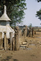 Montagnard village graveyard with carved wooden figures on posts in a squatting position with their hands over their faces Asian Southeast Asia Viet Nam Vietnamese Religion