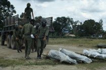 Vietnam War. Siege of Kontum. Montagnard soldiers wearing gas masks unloading dead bodies wrapped in plastic on stretchers from the back of a truckKon TumAsian Southeast Asia Viet Nam Vietnamese Lor...