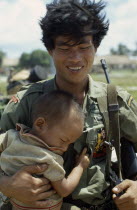 Vietnam War. Siege of Kontum. Montagnard soldier carrying young childKon TumAsian Southeast Asia Viet Nam Vietnamese Children Immature Kids