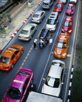 Thanon Ploenchit opposite Erawan Shrine.  View over three lanes of stationary traffic  brightly coloured meter taxis and two young Western women negotiating with Tuk-tuk driver.Late afternoon 4-5 pm....