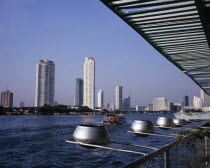 Chao Phraya River from Wat Ratchasungkhon decorated with silver alms bowls  high rise buildings on opposite bank including Shangri-La hotel and new apartments with river ferry departing north for Saph...