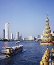 View across Chao Phraya River from Wat Ratchasungkhon decorated with gold umbrella usually sheltering Buddha in foreground with express river ferry  indicated by orange flag departing north for Saphan...