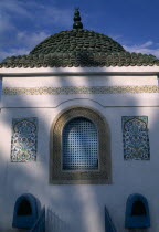 Part view of exterior of tomb with domed  tiled roof  arched window and decorative tiles.  Indistinct shadow falling across wall.funeralfuneraryburial placemausoleum African Middle East North Afri...