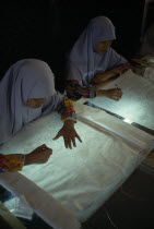 Young women tracing floral patterns first on to paper then transferring them to silk or satin.Asian Female Woman Girl Lady Immature Malaysian Southeast Asia Female Women Girl Lady Young Unripe Unripe...