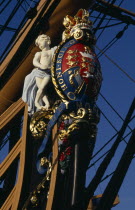 Admiral Lord Nelsons HMS Victory. Detail of elaborate figurehead of two cupids supporting the royal coat of arms and royal crown. The arms bear the Norman French inscription of the Order of the Garter...