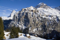 Houses on cliff edge with Eiger and Monch mountains in background.European Schweiz Suisse Svizzera Swiss Western Europe  Mountains Geography Winter Scenic