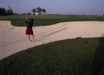 Doha Golf Club.  Male golfer playing out of a bunker on short nine hole floodlit course. 9 Middle East Old Senior Aged One individual Solo Lone Solitary Qatari